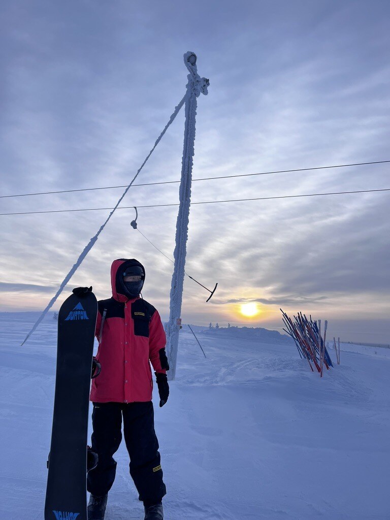 Snowboard in a snowy field at sunset