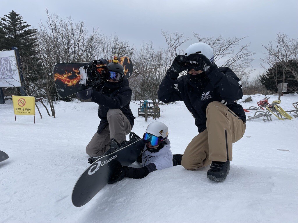 Three snowboarders posing in the snow