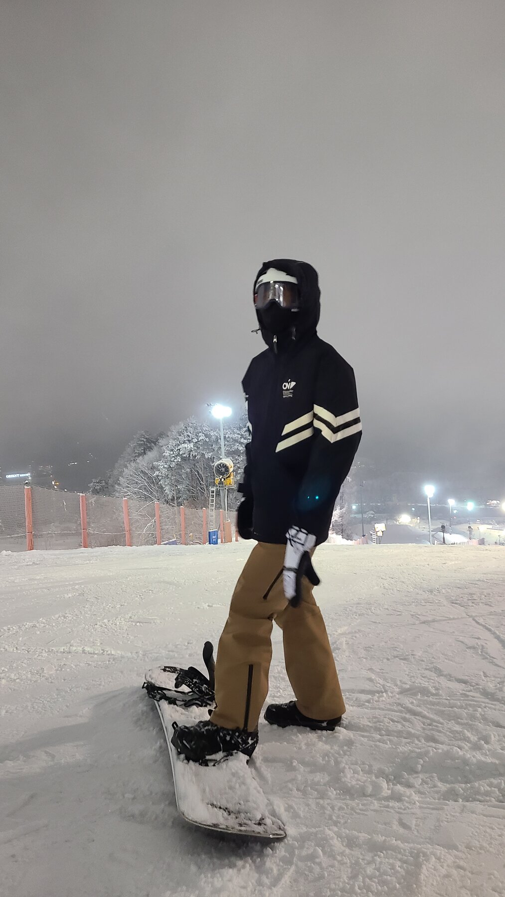 Standing on a snowboard at a snowy night resort