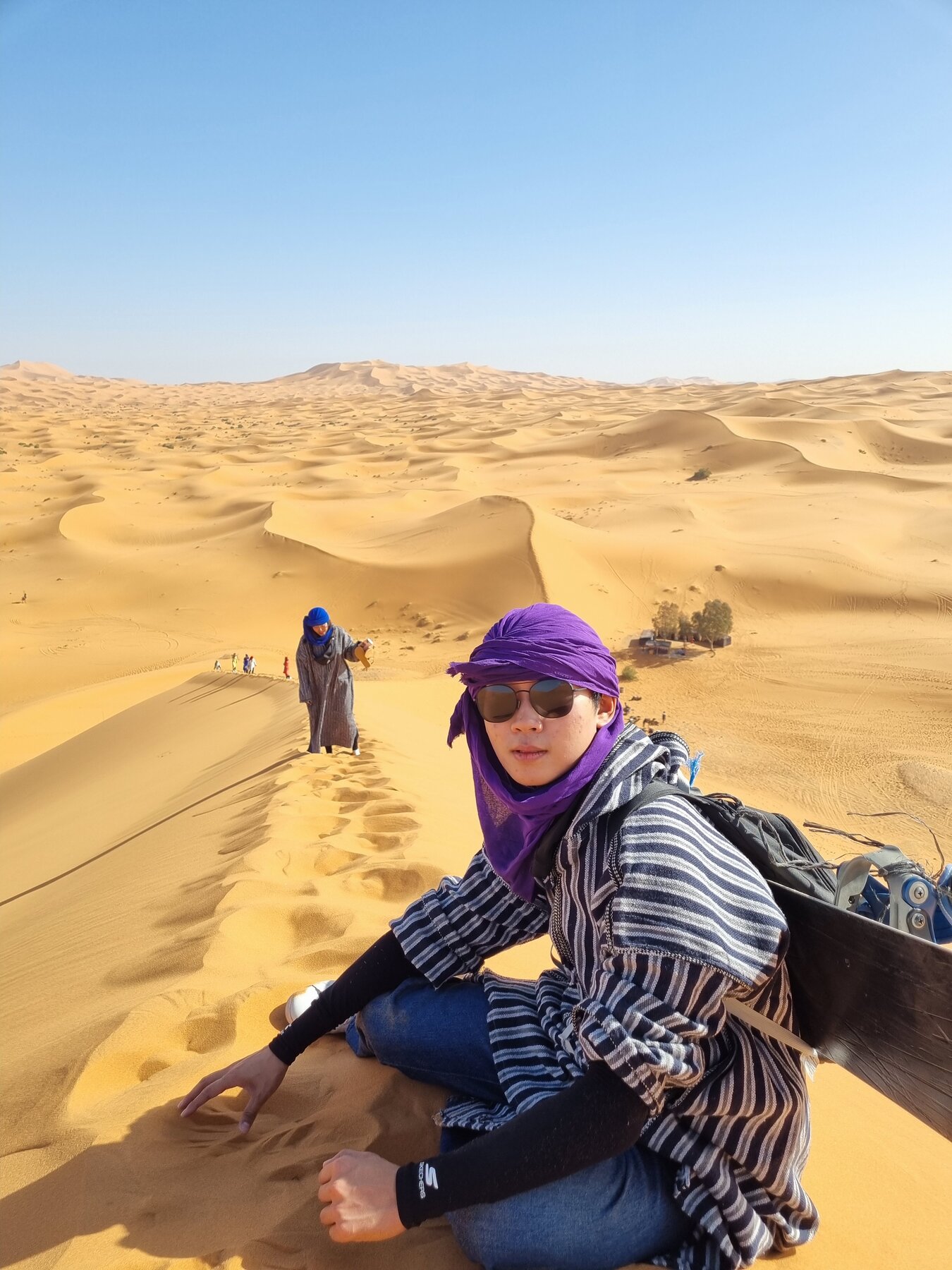 Sitting on a desert dune in a purple scarf
